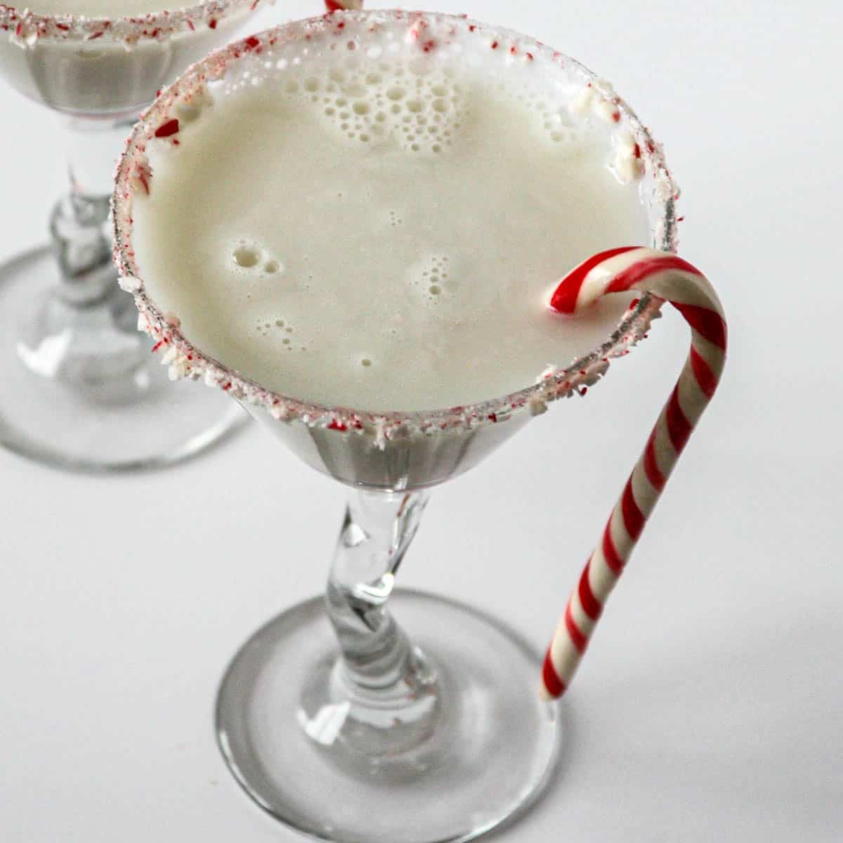 Candy cane martini in a martini glass, garnished with a candy cane.