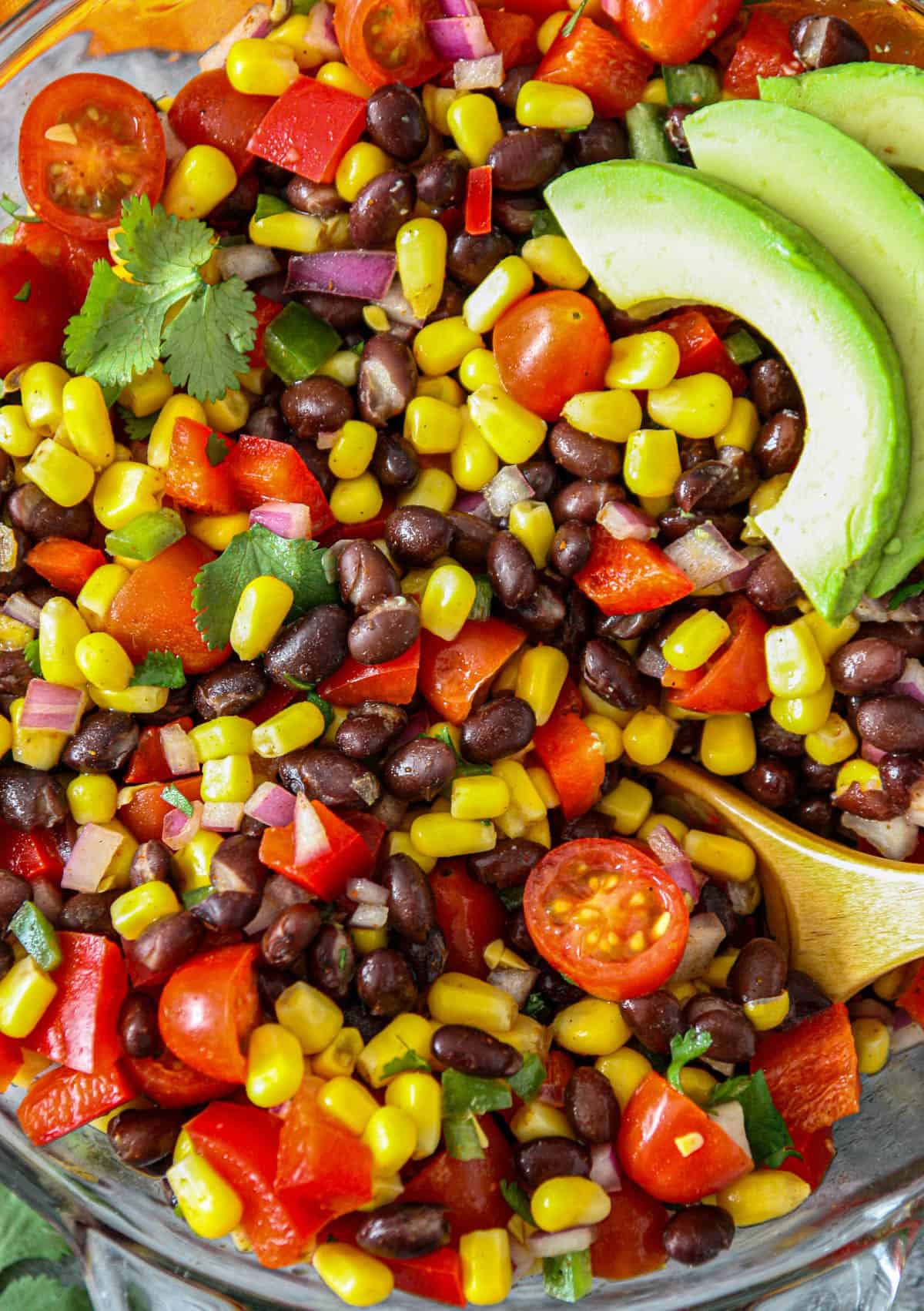 Fiesta salad in a glass bowl with a wooden spoon.