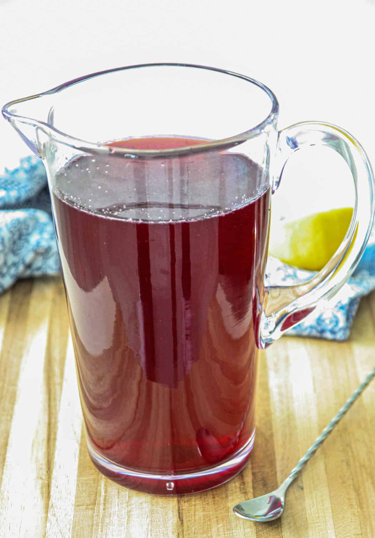 Tea, blueberry syrup, and lemon juice combined in a clear pitcher.