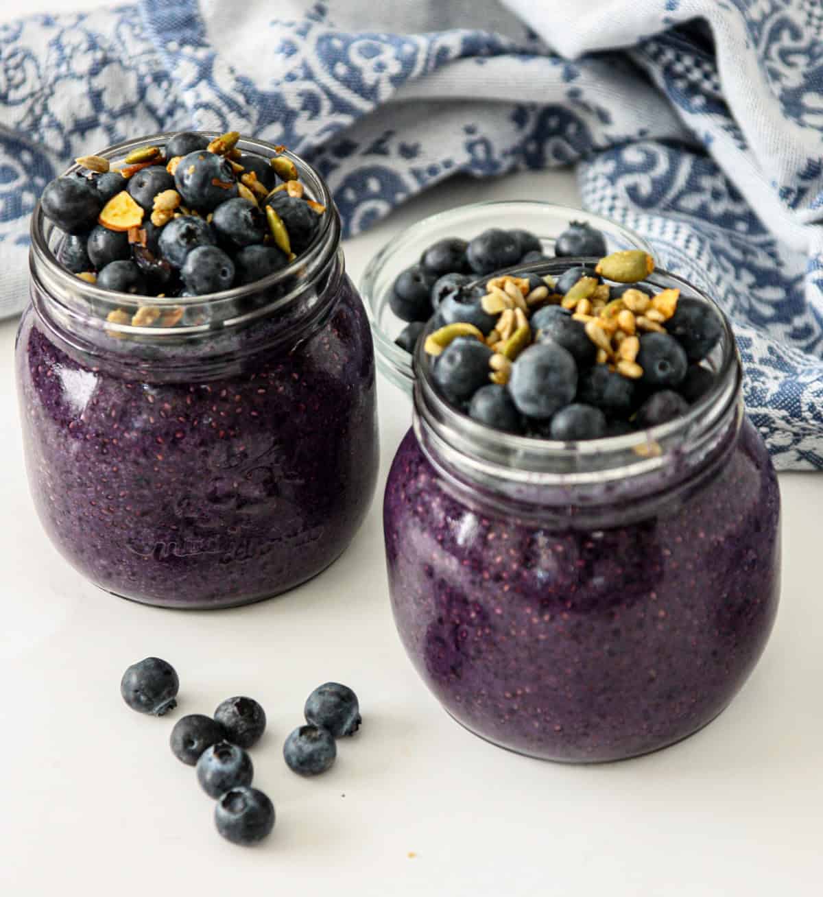 Blueberry chia pudding in two glass jars, topped with fresh blueberries.