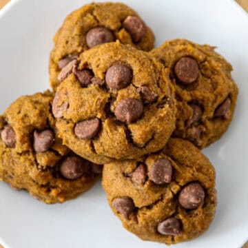 Five gluten free pumpkin cookies on a white plate.