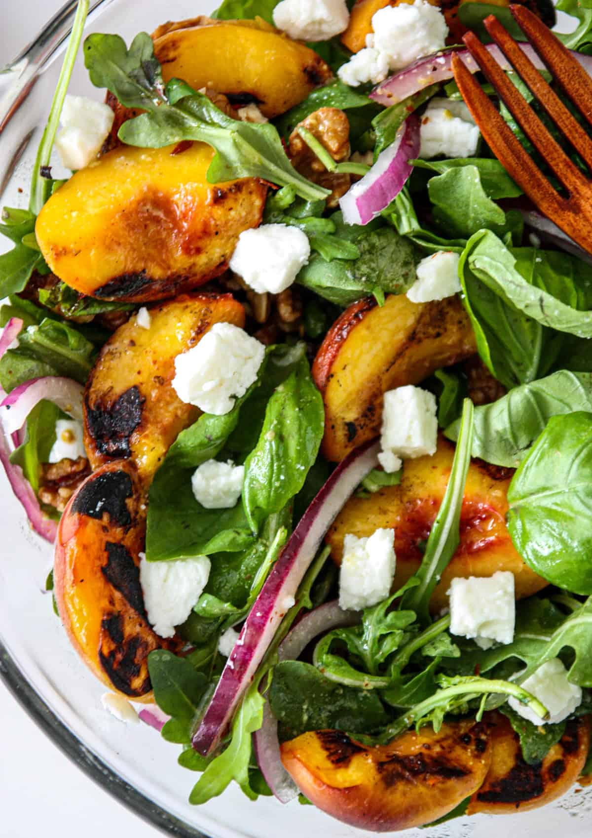 Grilled peach salad with a wooden fork.