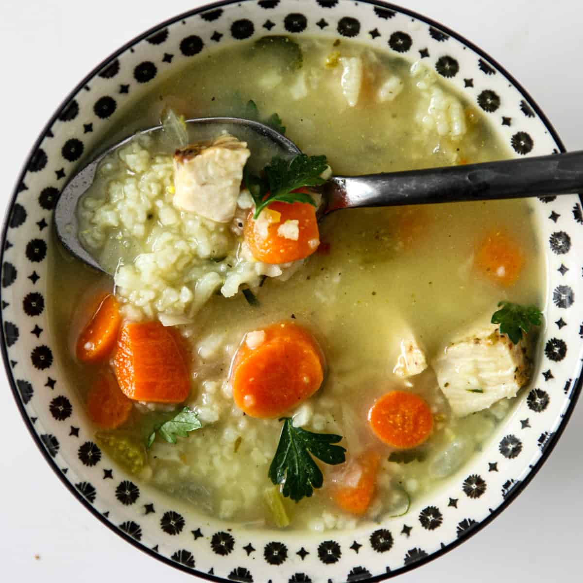 Turkey and rice soup in a black and white bowl.